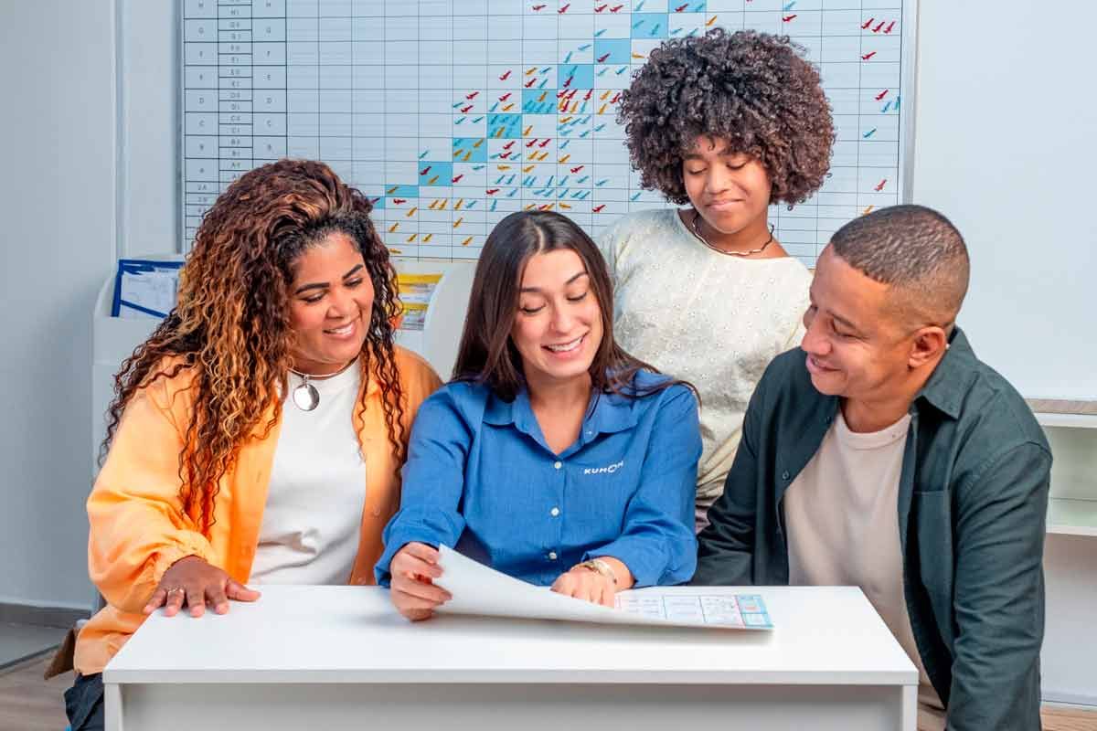 Pai, mãe, filha e orientadora do Kumon explicando como funciona o método de estudos