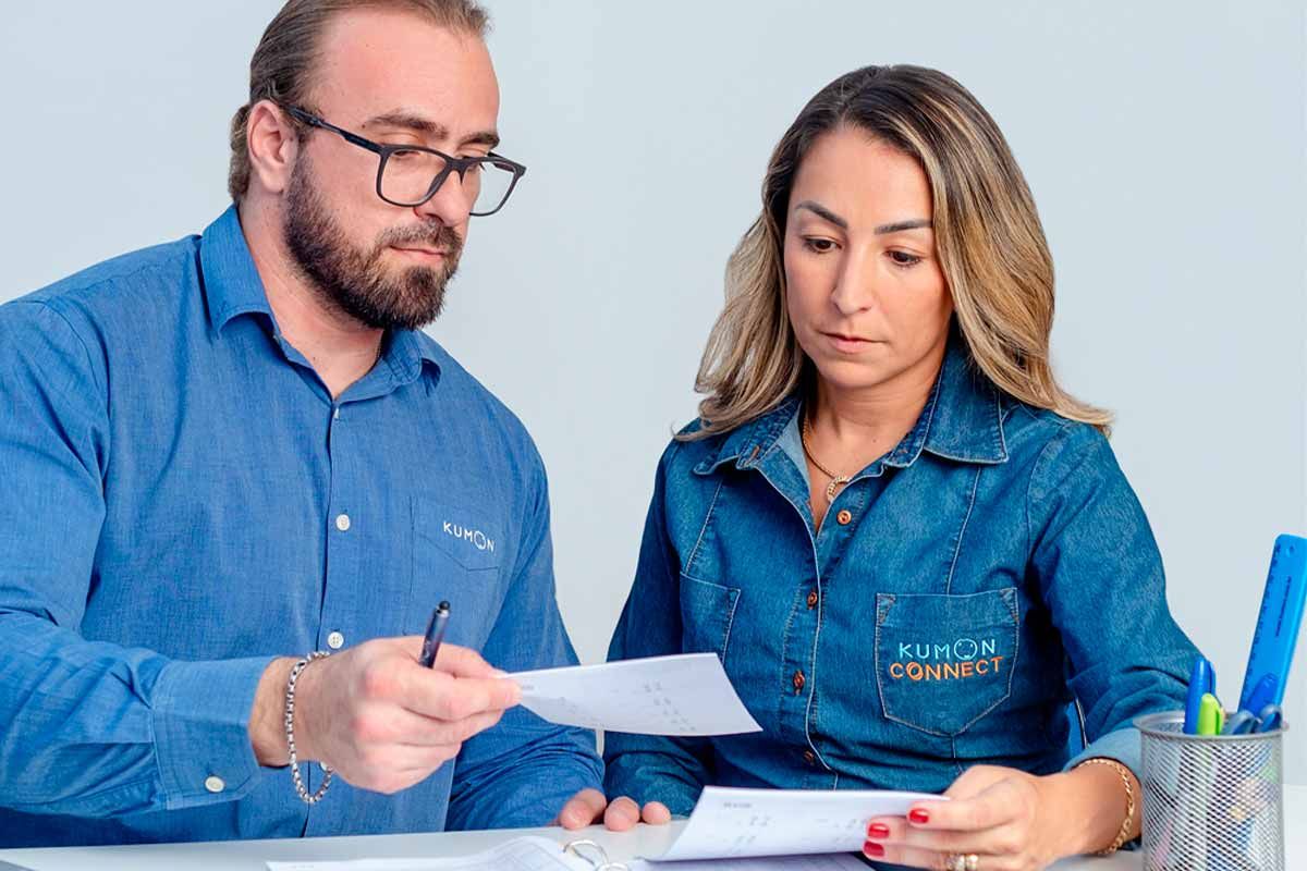Colaborador da empresa Kumon explicando como funciona a rotina de estudos e o material didático