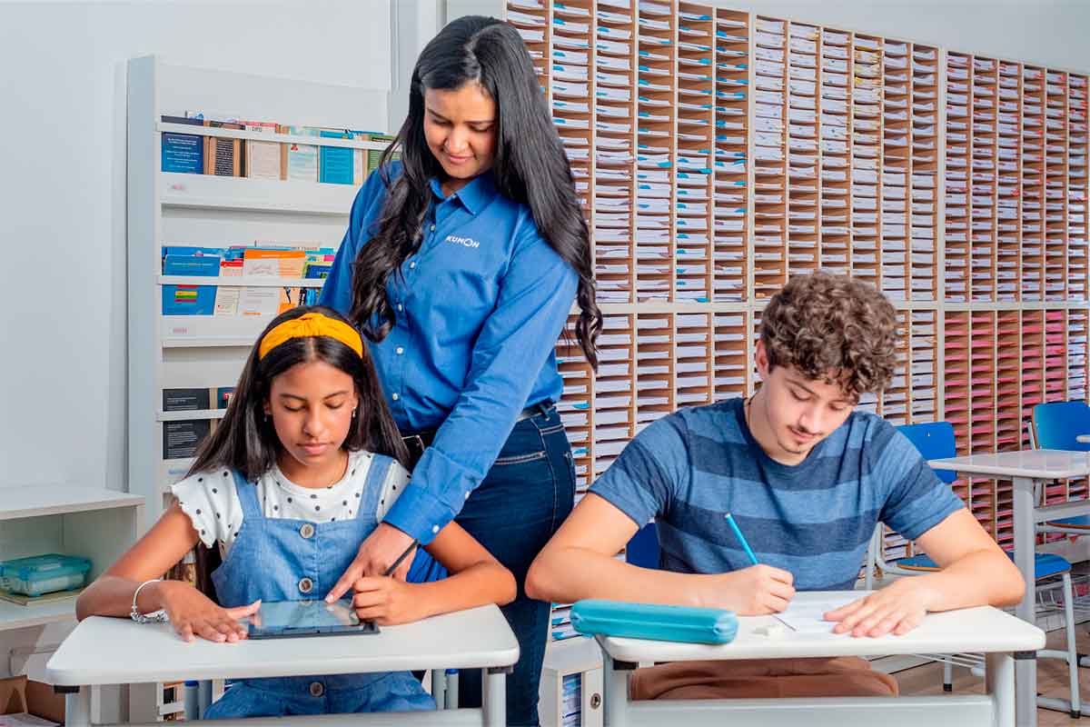 Orientadora do Kumon observando dois alunos estudando